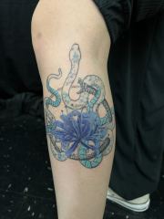 Ouroboros-with-spider-lilly-in-blue-on-leg