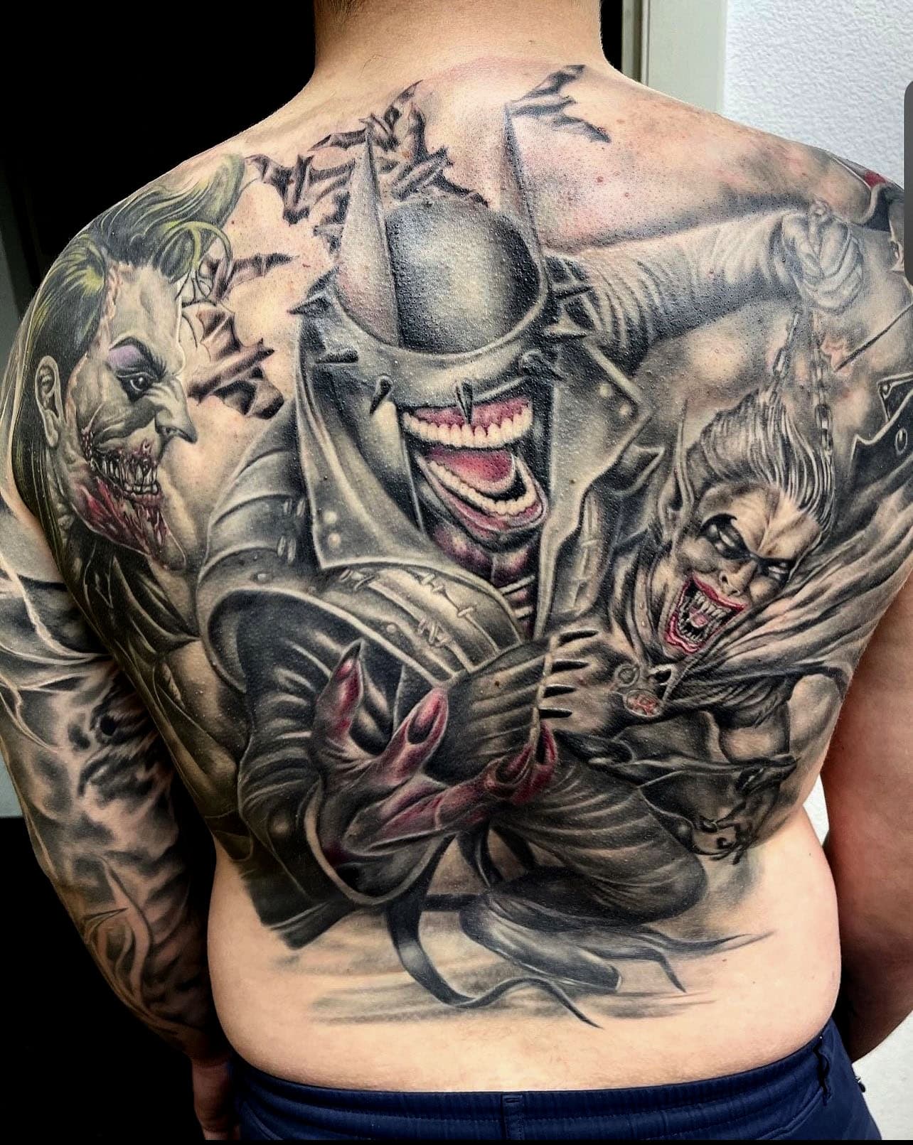 The batman who laughs Backpiece Tattoo, with the Joker on the left shoulder and The Penguin on the right should as Robin gets Dragged along, By Don At Art In Motion Tattoos